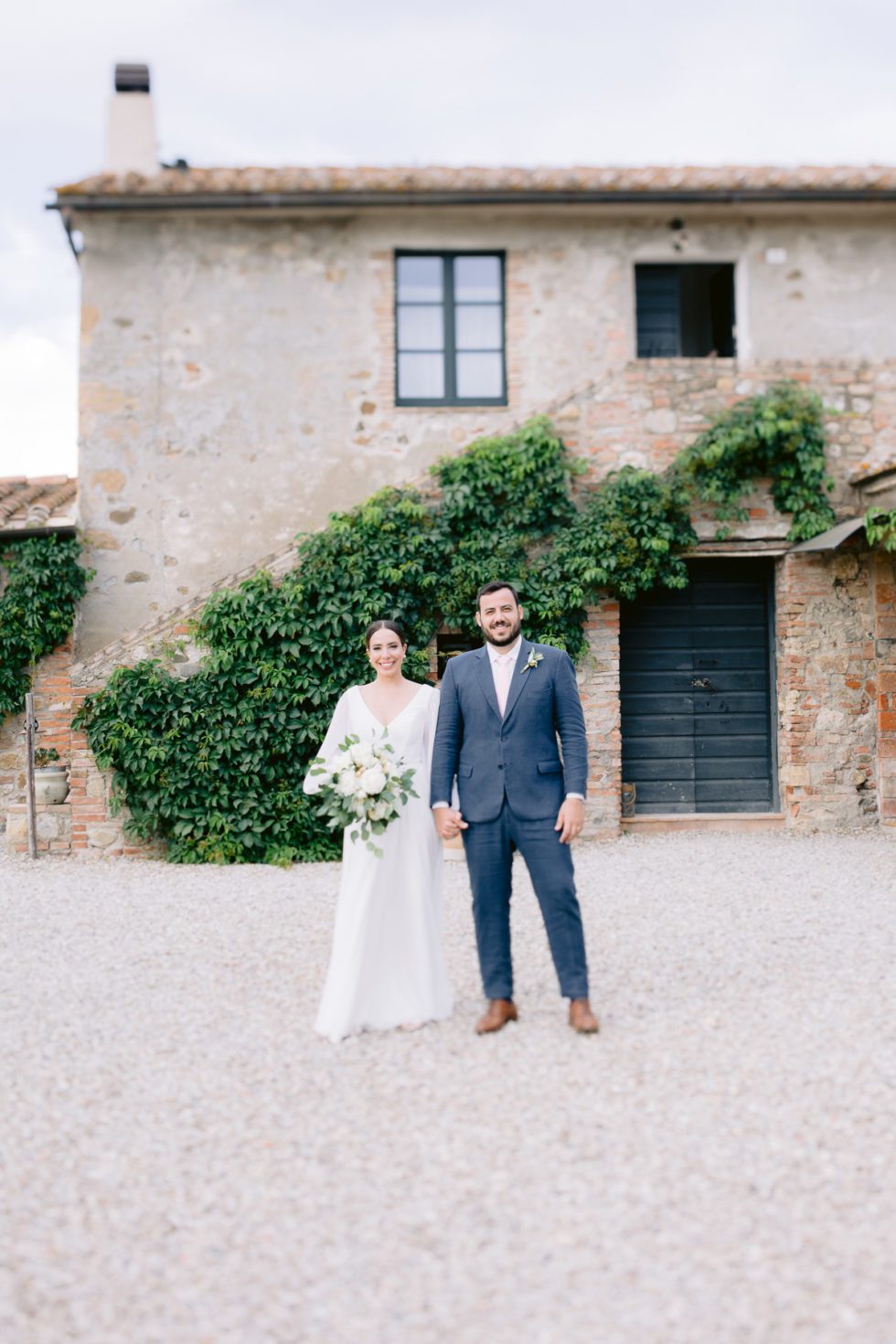 Couple posing for a portrait in front of Locanda in Tuscany